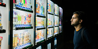 Man in front of vending machines at night. Photo by Victoriano Izquierdo on Unsplash